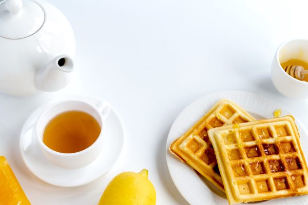 Breakfast products composition Breakfast products composition. Waffles, tea and lemon. White background