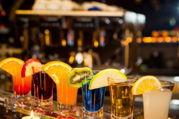 Side view cocktail shots with slice of lemon and kiwi slice and candles on bar background Side view cocktail shots with slice of lemon and kiwi slice and candles on bar background